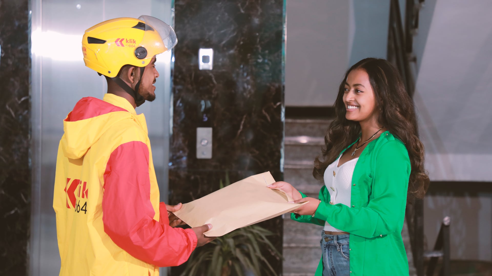 klik rider handing a sealed envelope to a professional in an Addis Ababa office lobby